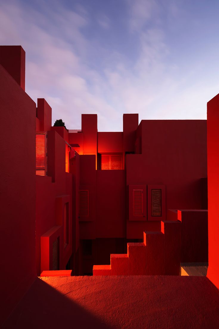 red building with stairs leading up to the top floor and sky in background at dusk