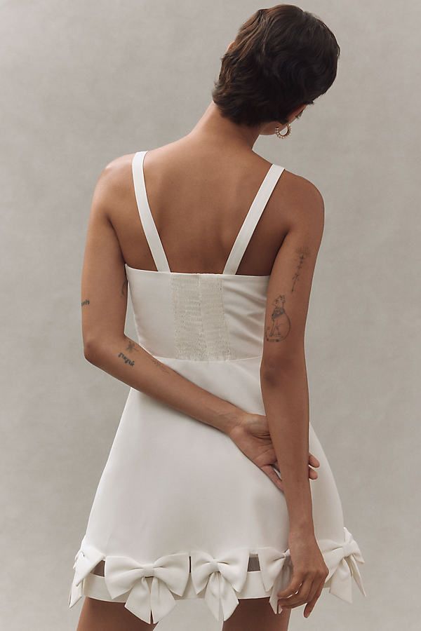 An understated silhouette gets an unexpected twist in this mini number by Sachin & Babi. The dress features a sleek, fitted design that dramatically ends with oversized bows at the hem, adding a playful, party-ready spin. | Square-Neck Bow-Hem Mini Dress by Sachin & Babi in White, Women's, Size: Medium, Polyester at Anthropologie Wedding Mini Dress With Tie Back And Fitted Bodice, A-line Mini Dress With Tie Back And Fitted Bodice, Brunch Mini Dress With Tie Back And Fitted Bodice, Fitted Bodice Mini Dress With Tie Back For Brunch, Fitted Tie-back Mini Dress For Wedding, Fitted Mini Dress With Tie Back For Brunch, Fitted Mini Dress With Tie Back For Wedding, Mini Dress With Back Zipper For Wedding, Chic Mini Dress With Back Zipper For Brunch