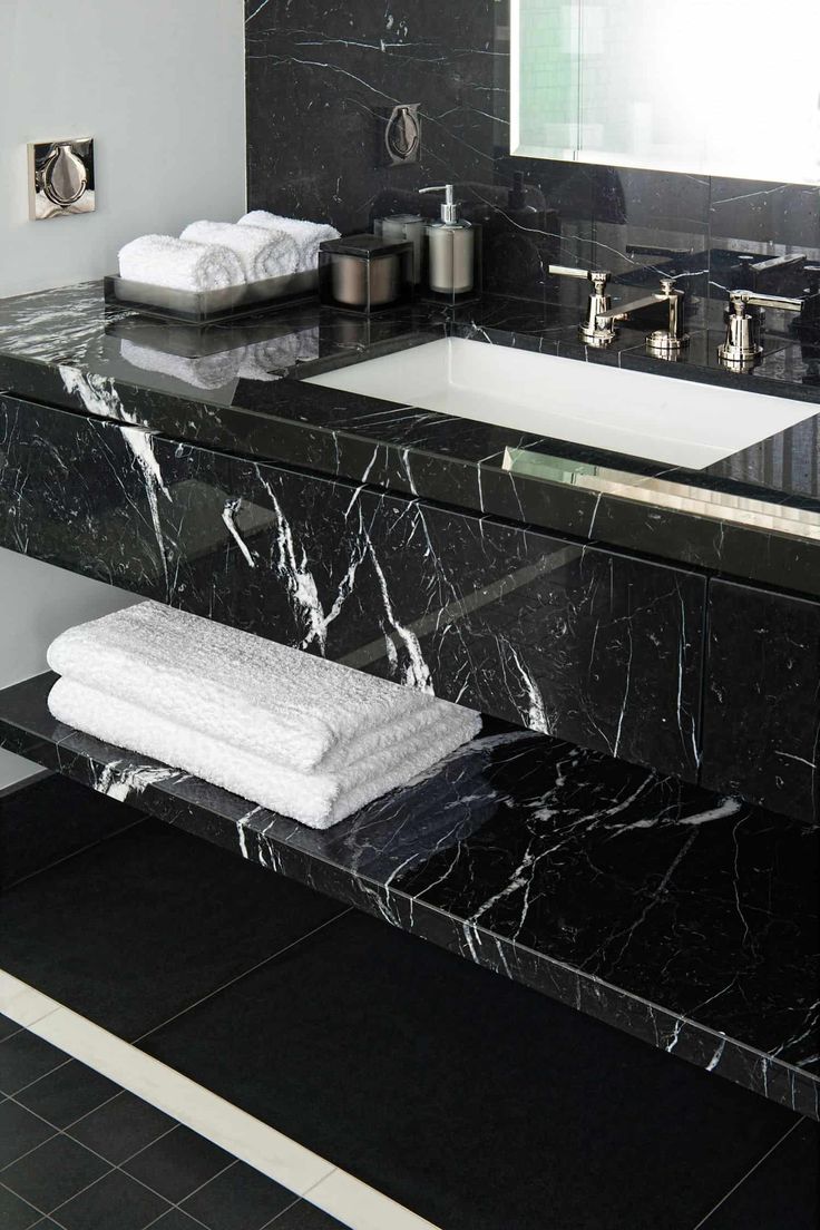 a bathroom with black marble counter tops and white towels