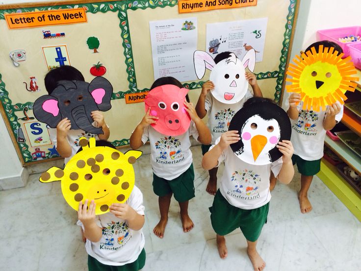 children holding up masks in front of their faces with animals and giraffes on them