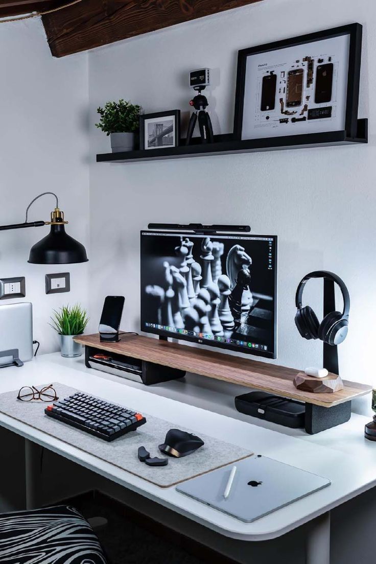 a desk with a computer monitor, keyboard and headphones on it in a home office