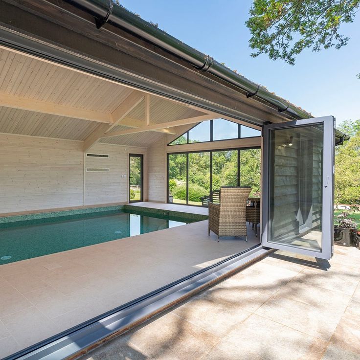 an indoor swimming pool in the middle of a house with glass walls and sliding doors