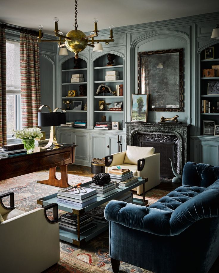 a living room filled with furniture and bookshelves next to a window covered in curtains