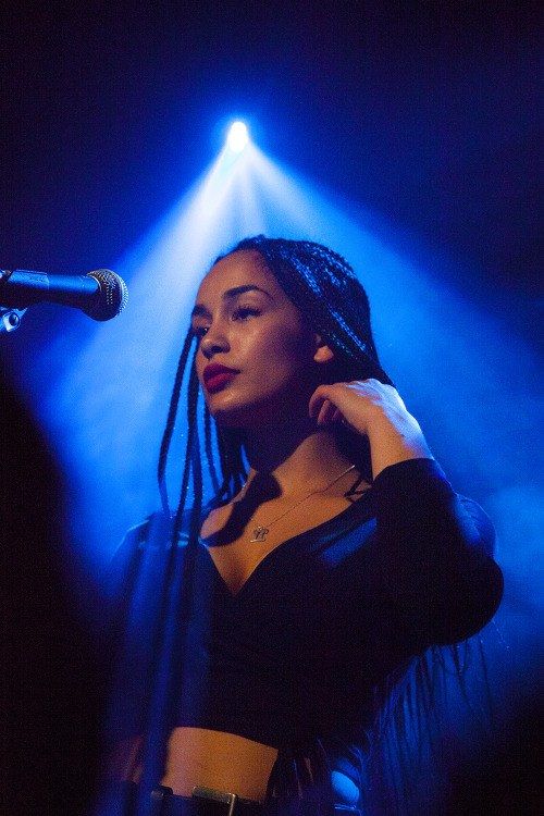 a woman with dreadlocks on her head standing in front of a microphone at a concert