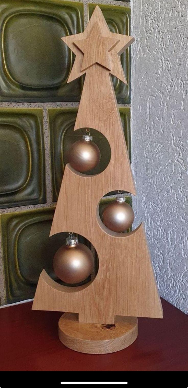 a wooden christmas tree with three silver balls in the shape of a star on top