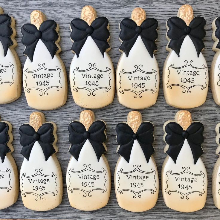 decorated cookies are arranged in the shape of bottles with black bow ties and labels on them