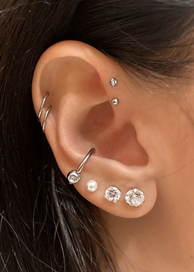 a woman's ear with three different piercings