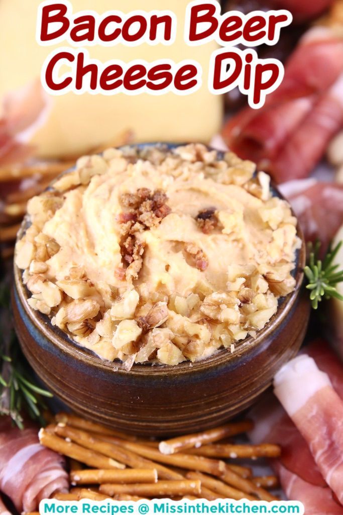 bacon beer cheese dip in a wooden bowl surrounded by pretzels and crackers