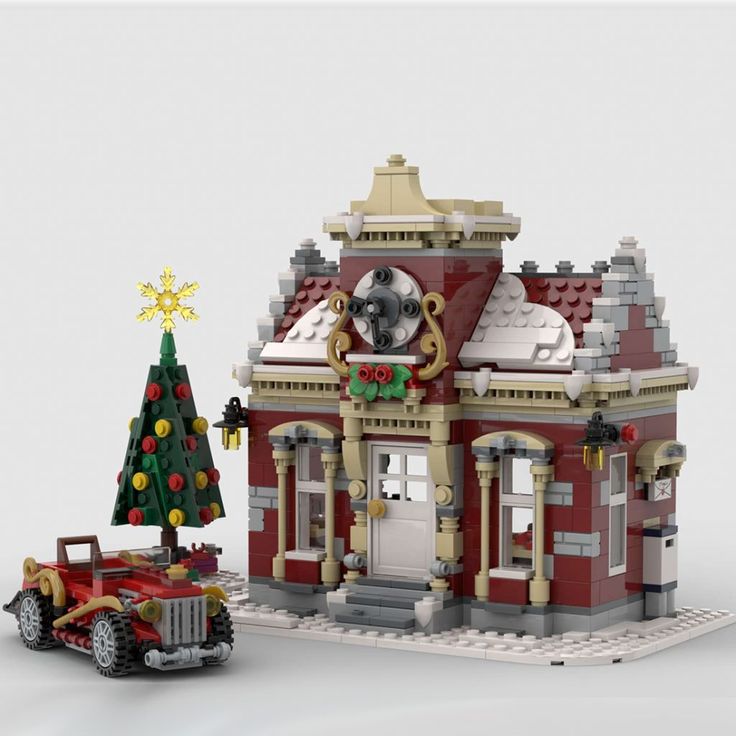 a red and white building with a christmas tree in front of it next to a toy firetruck