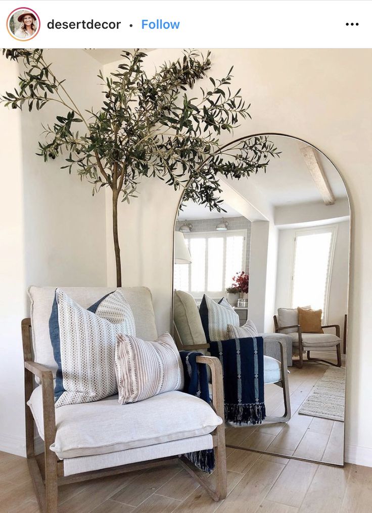 a living room filled with furniture and a tree in the middle of the room next to a mirror