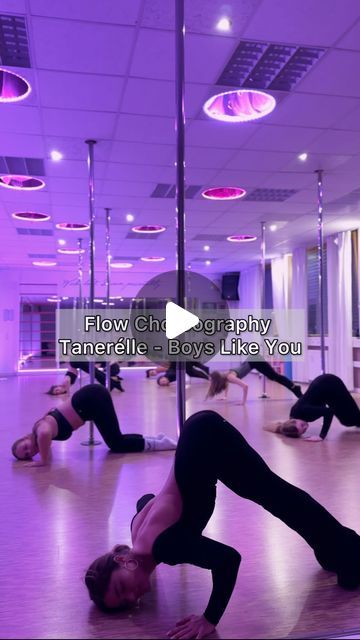 a group of people doing yoga poses in a room with purple lights and circular chandeliers