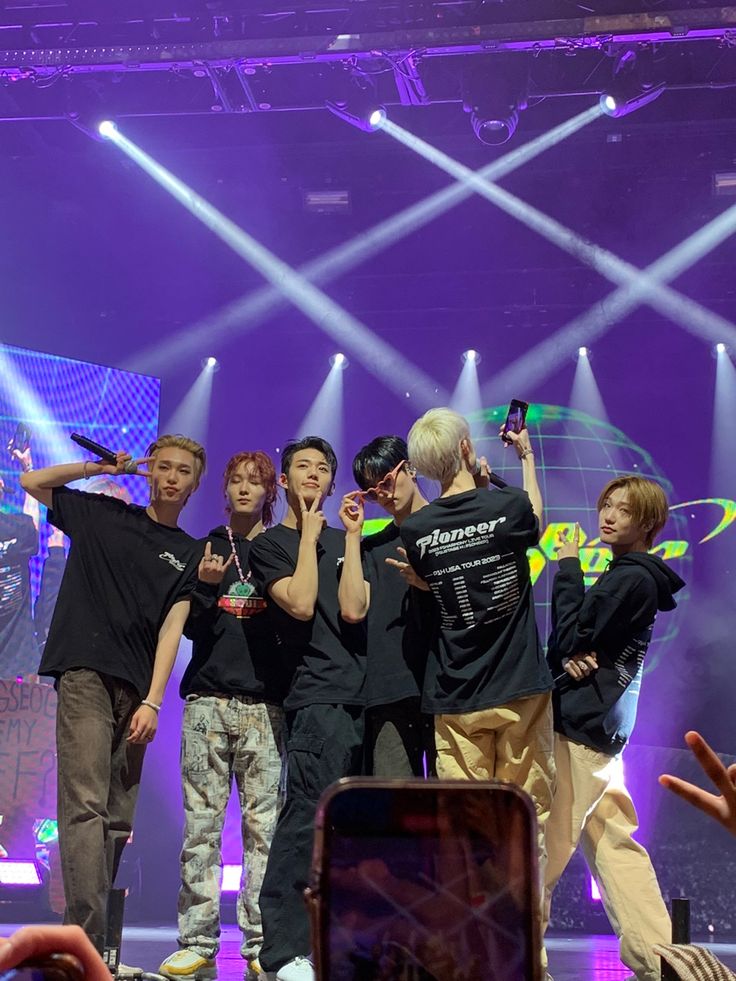 a group of young men standing on top of a stage with their hands in the air