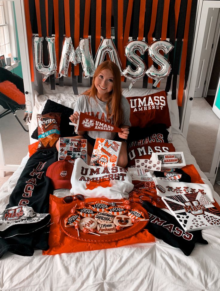 a woman sitting on top of a bed covered in pillows and t - shirt designs