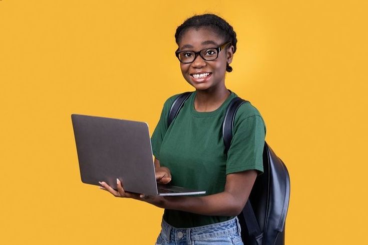 a woman with glasses is holding a laptop computer and smiling at the camera while standing against a yellow background