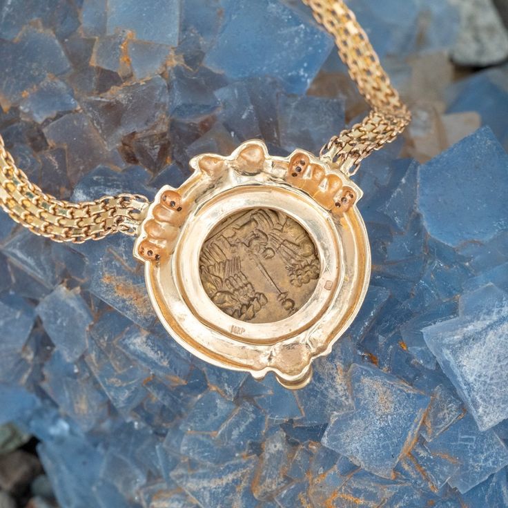 This gorgeous Robert Bartholomew designed pendant is centered with an Italian gold toned base metal token. The token depicts on the obverse with a Roman woman in profile wearing a leaf headdress, earrings and a beaded necklace. The reverse of the token depicts a soldier scene. The frame of the pendant is accented with one (1), bezel set, round cabochon cut natural emerald and twelve (12), bead set, round brilliant cut diamonds. The pendant measure 30mm wide and is attached to a 14k yellow gold f Gold Byzantine Jewelry With Intaglio Details, Antique Gold Coin Pendant Jewelry, Antique Gold Coin Pendant Jewelry For Collectibles, Antique Gold Jewelry With Coin Pendant, Antique Gold Jewelry With Coin Pendant For Collectors, Commemorative Medallion Coin Pendant Jewelry, Commemorative Coin Pendant Medallion Jewelry, Victorian Style Medallion Coin Pendant Jewelry, Bronze Medallion Jewelry For Commemoration