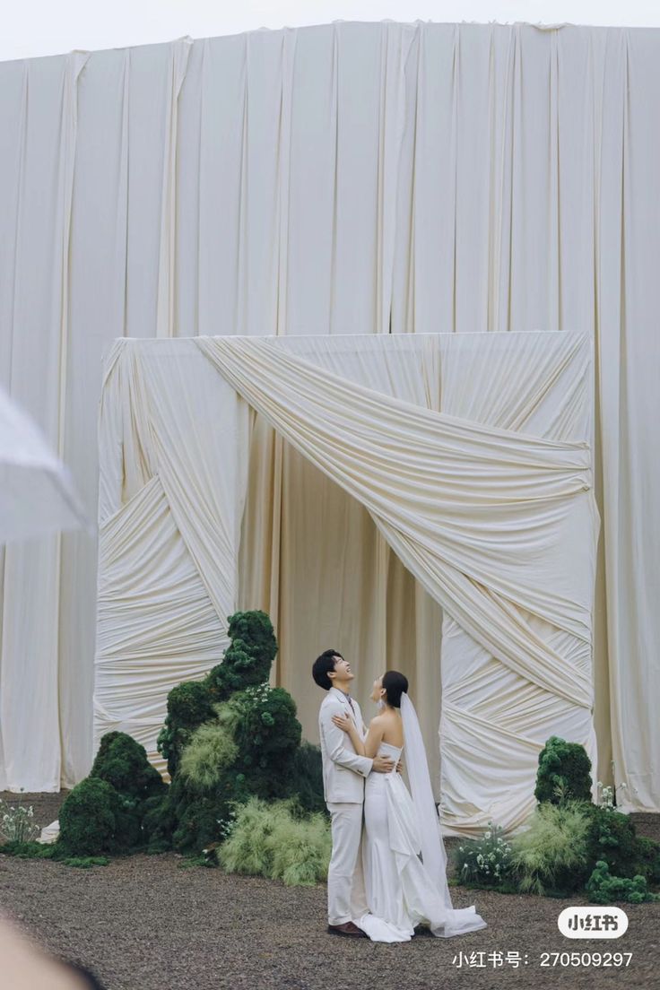 two people standing in front of a white curtain