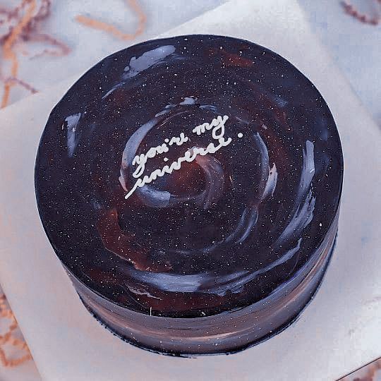 there is a black cake with purple and blue swirls on the top that says, you're my sunshine