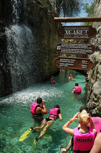 several people in pink life jackets are paddling through the water near a sign that says xcarfa