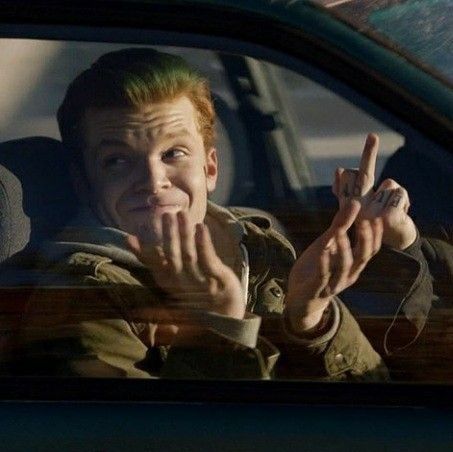 a man sitting in the back seat of a car holding his hand up and making a peace sign