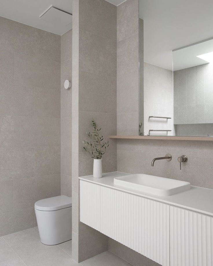 a bathroom with a sink, toilet and large mirror above the sink is featured in an instagram