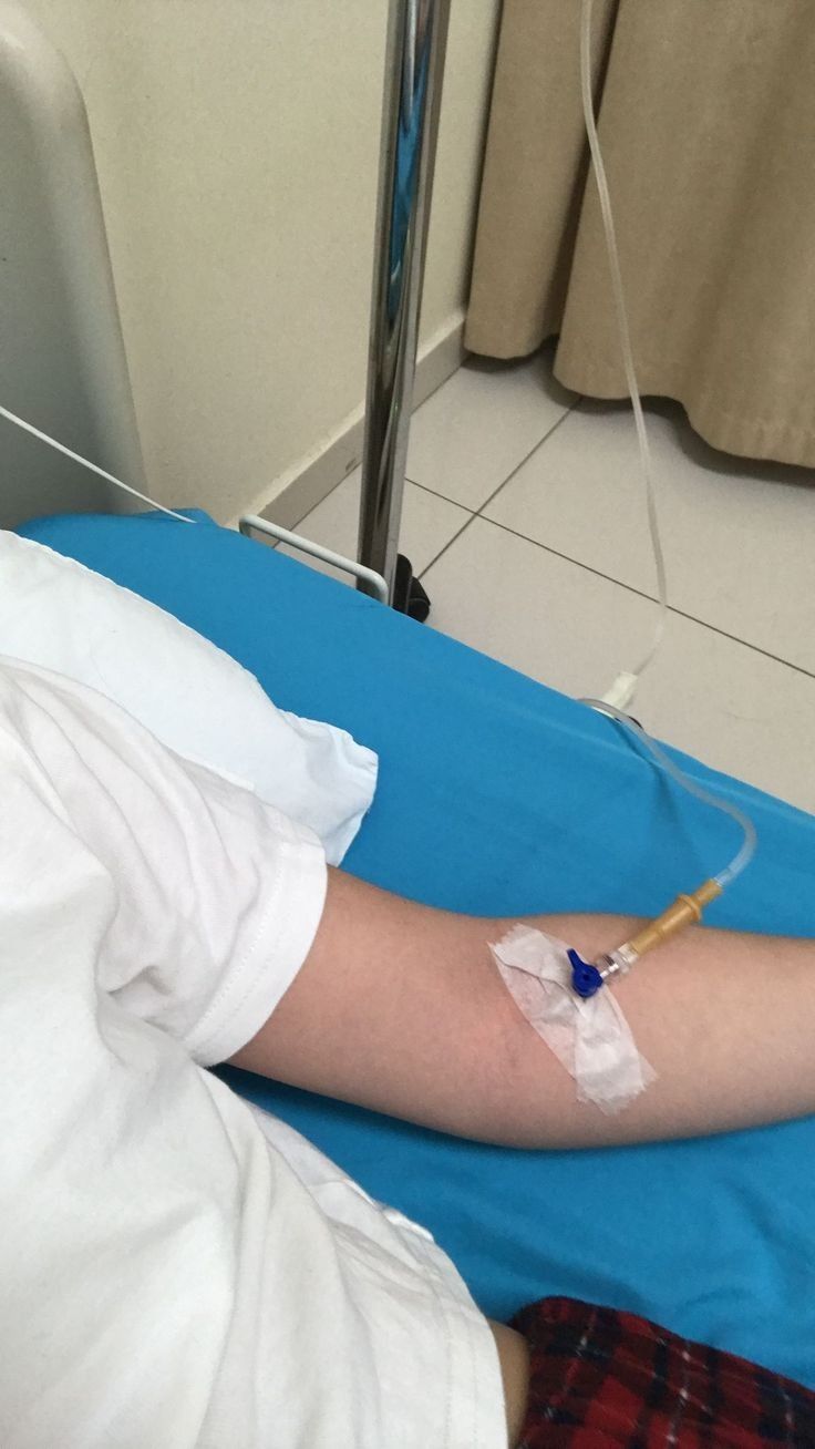 a person laying in a hospital bed with an iv tube attached to their arm and hand