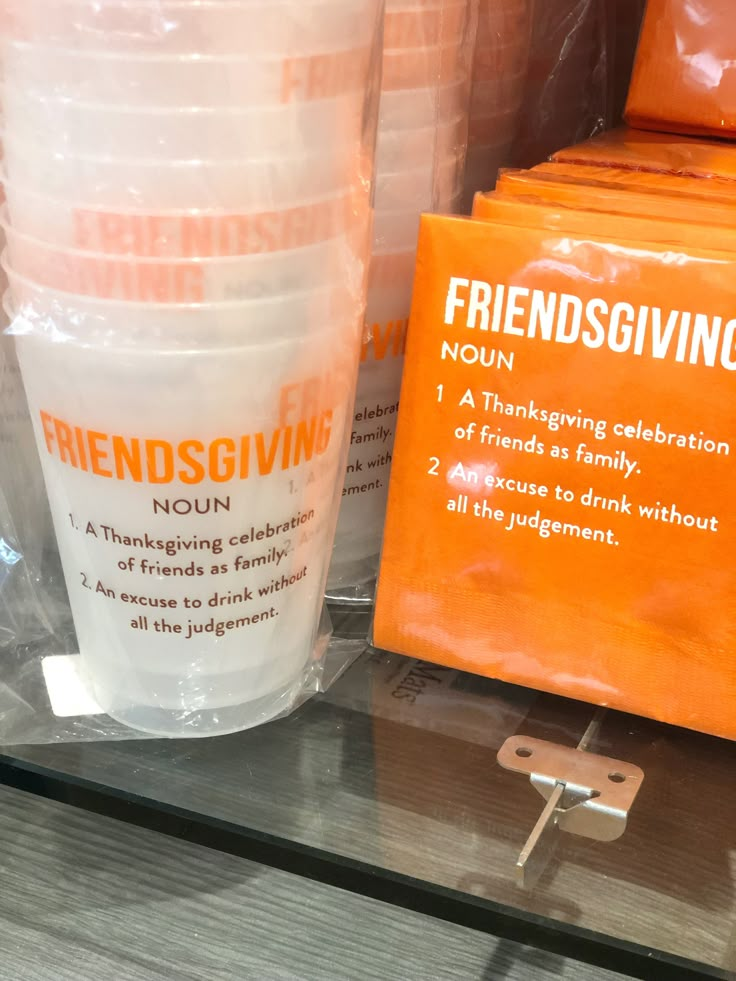 plastic cups are sitting on a shelf in a store with an orange sign next to them