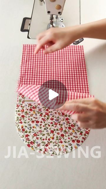 someone is using a sewing machine to sew fabric on a piece of red and white cloth