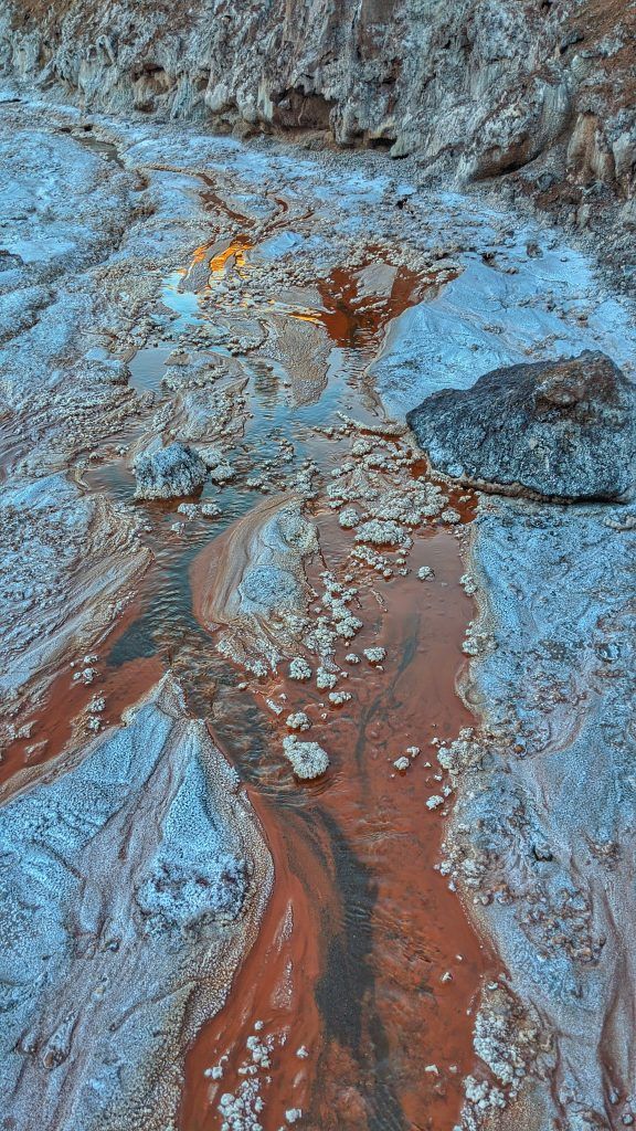 some rocks and water in the middle of a river with red, white and blue colors