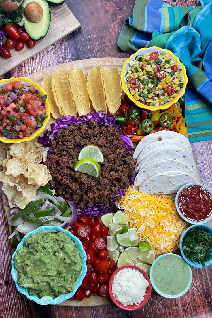 a platter filled with tacos, guacamole, salsa and tortilla chips