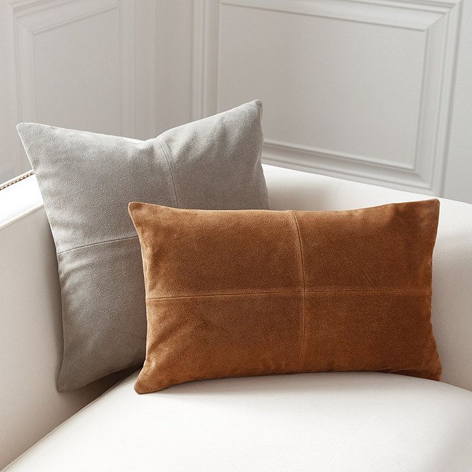 two pillows sitting on top of a white couch