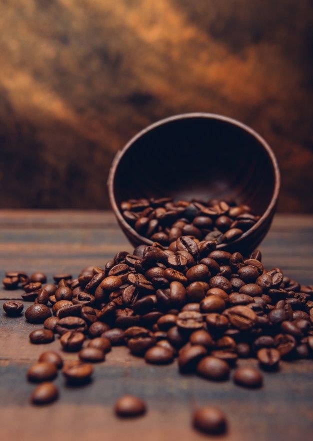 a wooden bowl filled with coffee beans on top of a table