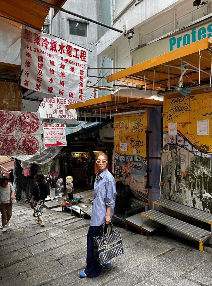 a man is standing in front of a building with signs hanging from the ceiling and people walking around