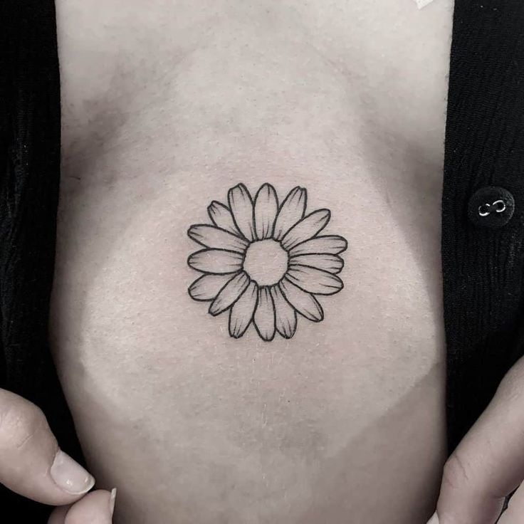 a black and white photo of a woman's stomach with a flower tattoo on it