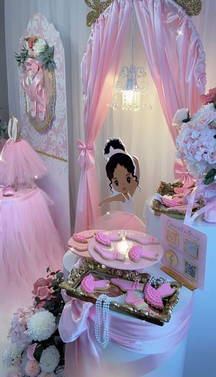 a doll is sitting on top of a table with pink and gold decorations around it