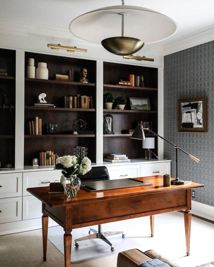 an iphone photo of a desk and bookshelves in a home office with gray walls