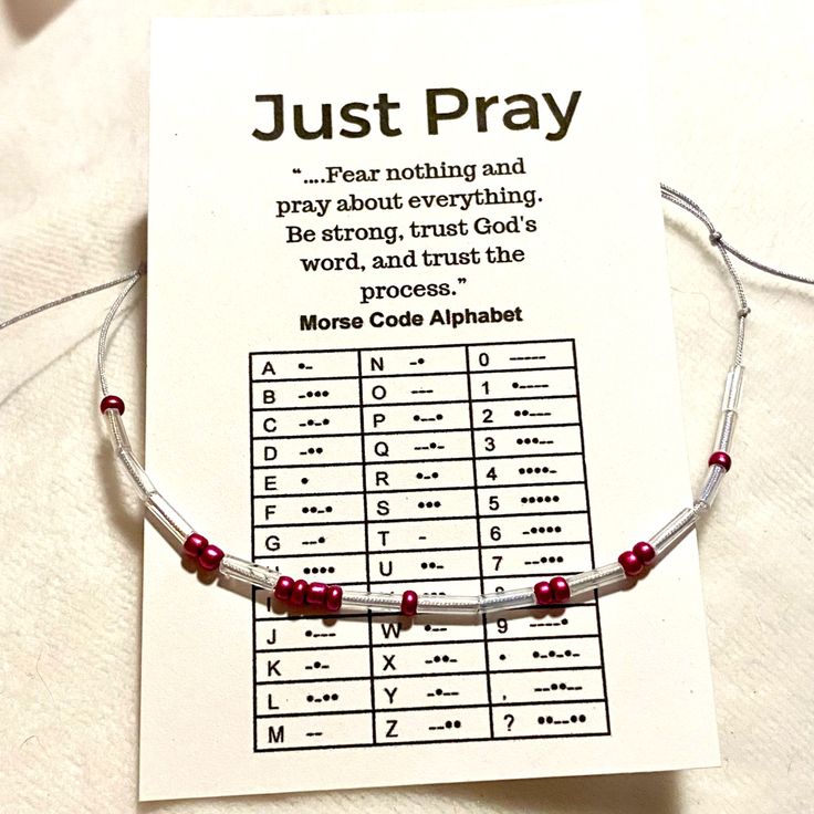 a bracelet with red beads on it sitting on top of a piece of paper that says just pray