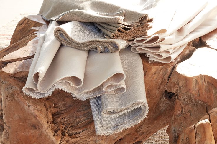 several folded towels sitting on top of a piece of drifty wood in the sun