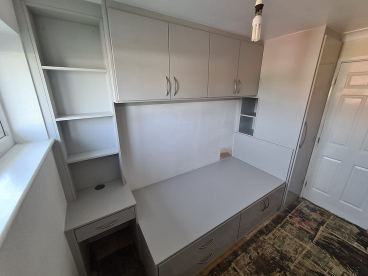 an empty room with white cabinets and drawers