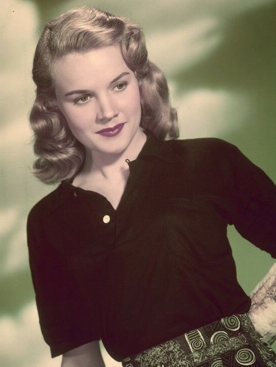 an old photo of a woman with her hands on her hips wearing a black shirt and patterned skirt