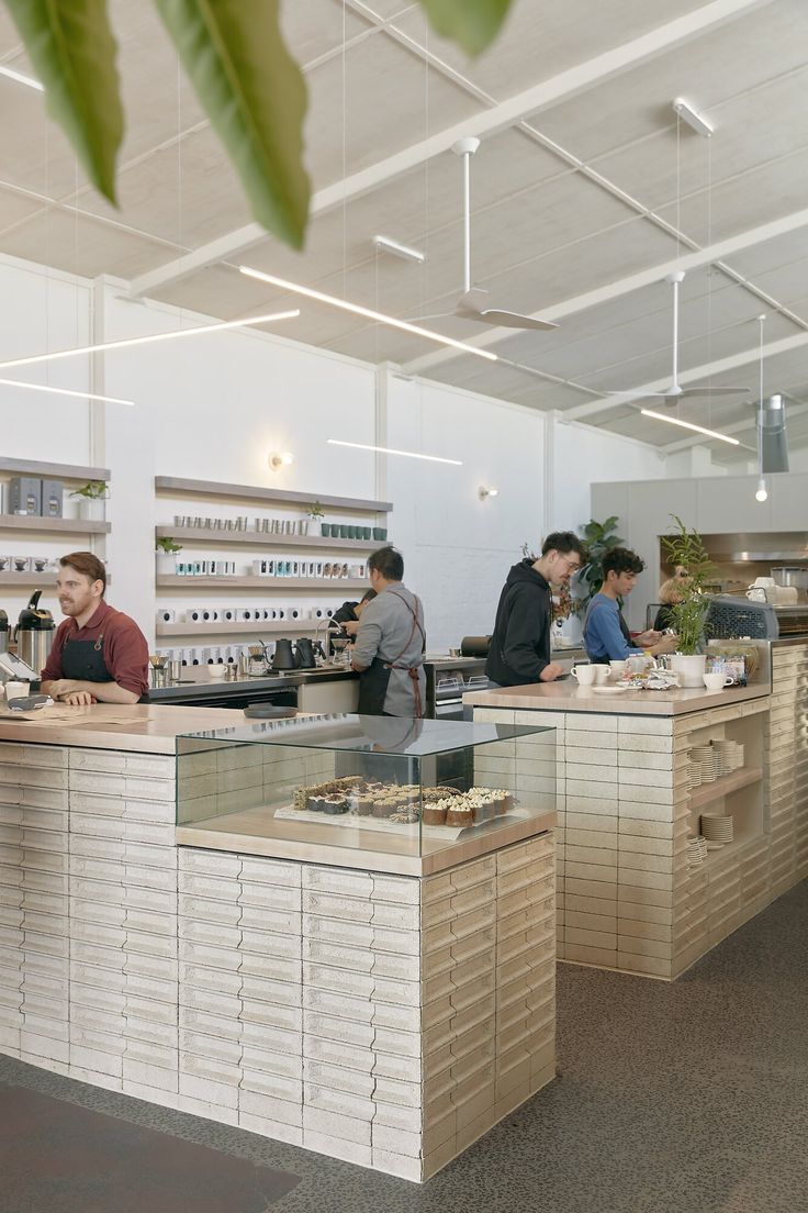 people are working at the counter in an open air store with lots of shelves on each side