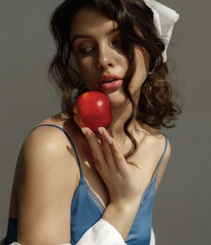 a woman in blue dress holding an apple