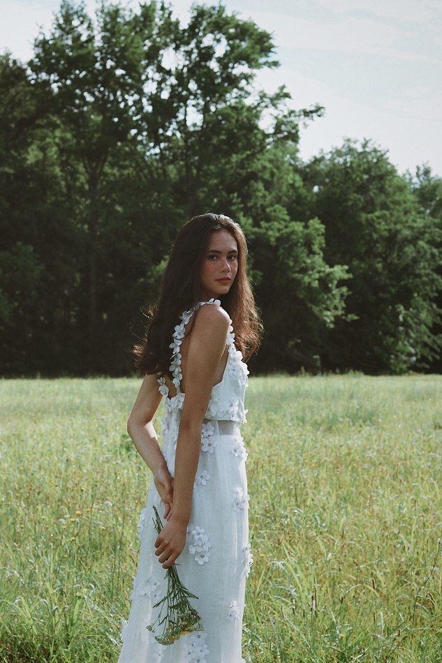 a woman in a white dress standing in a field