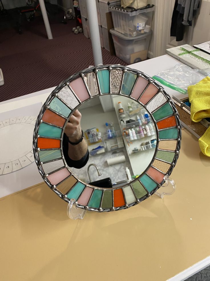 a person holding up a colorful mirror on top of a counter