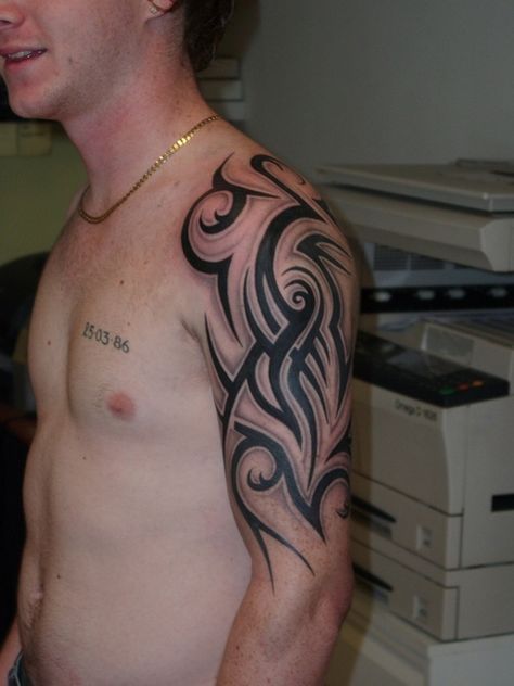 a man with a tattoo on his arm and chest standing in front of a printer