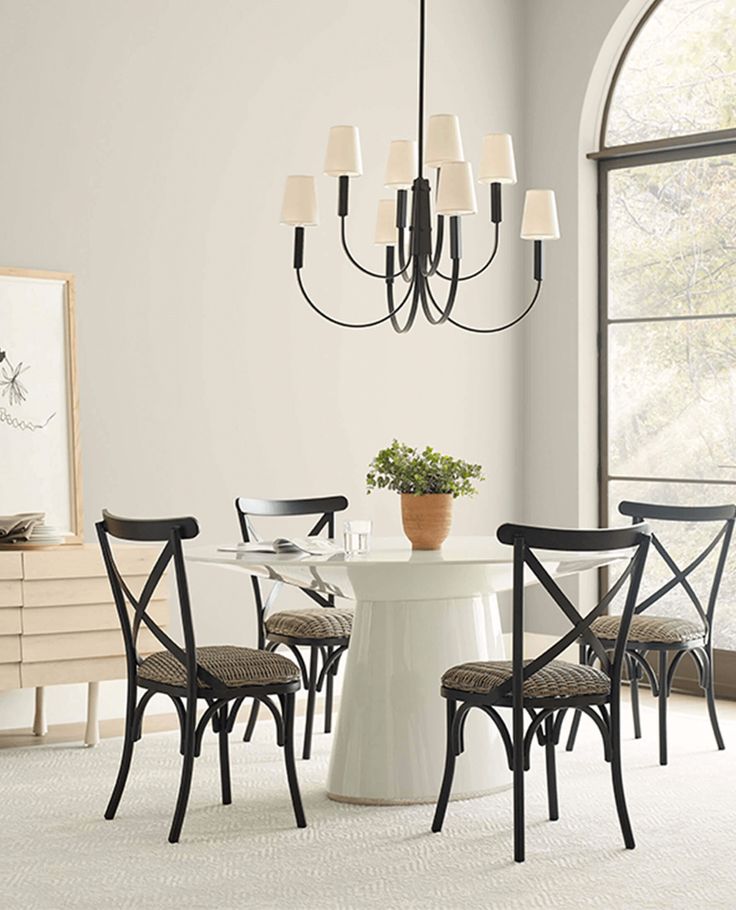 a dining room table with four chairs and a potted plant on the table next to it