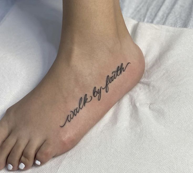 a woman's foot with the words walk by faith written on her left side