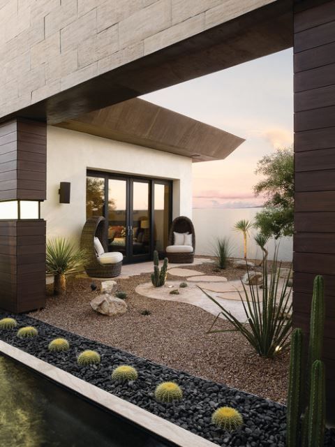 a modern house with cactus and rocks in the front yard