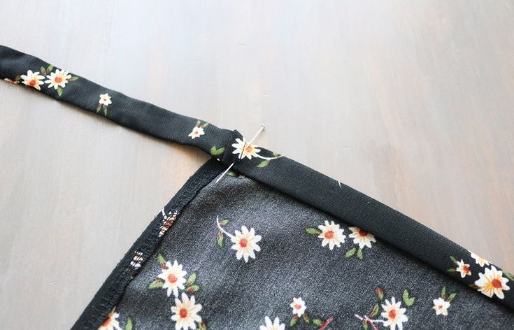 a piece of fabric with flowers on it laying on a wooden floor next to a pair of scissors