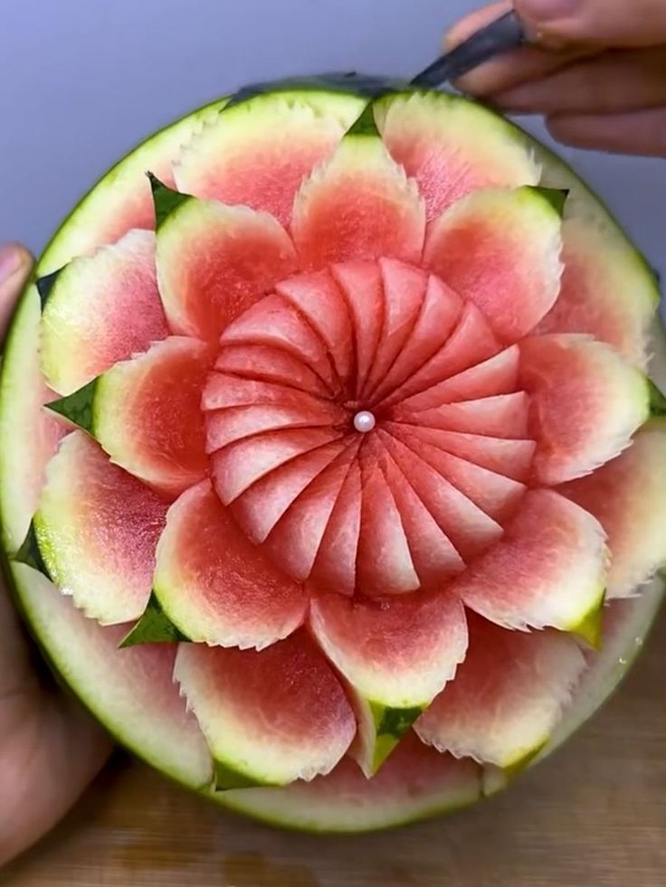 a person cutting into a watermelon flower on top of a piece of fruit