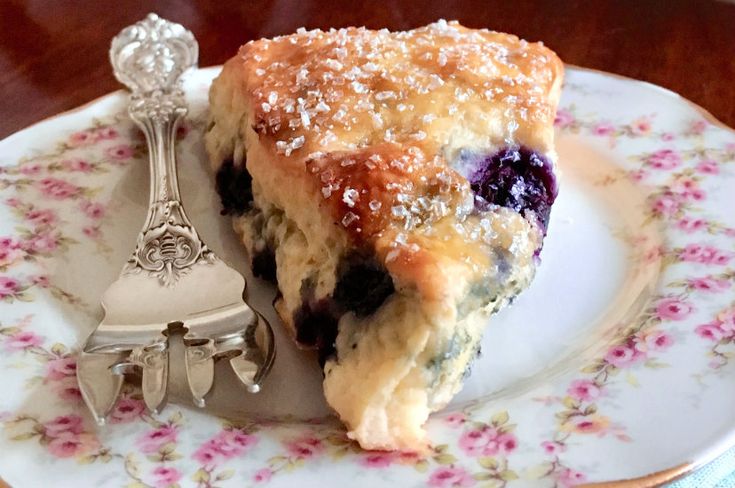 a piece of blueberry pie sitting on top of a plate next to a fork